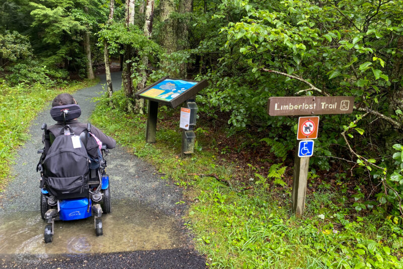 a wheelchair user navigates a paved trail with directional signage