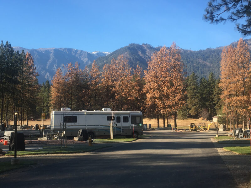 an rv is parked at a campground surrounded by mountains and golden fall foliage
