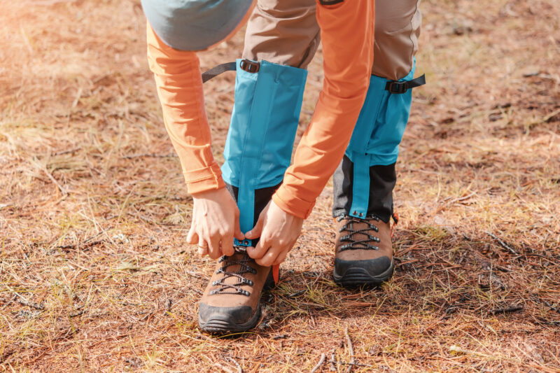 a hiker snaps gaiters over trekking boots outside