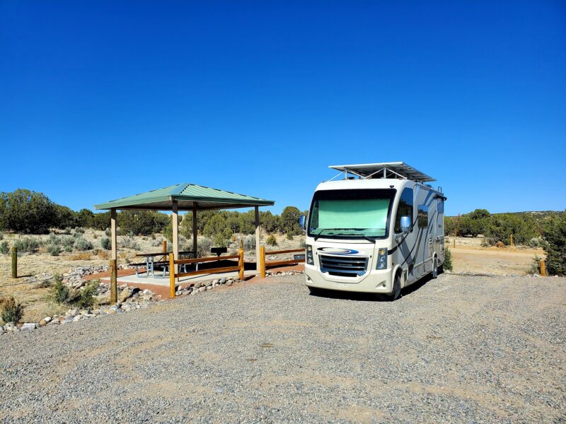an rv is parked at a campsite under a clear blue sky