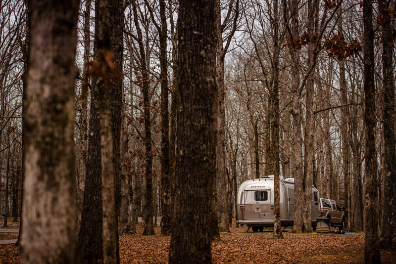 an airstream trailer is parked in a wooded campground