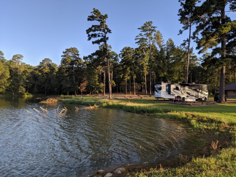 an rv is parked at a campsite near a lake surrounded by trees