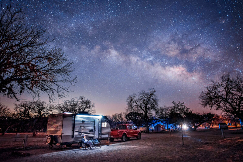 an rv is parked under a blanket of stars at night