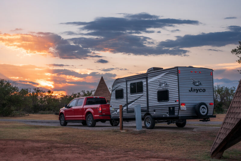 a red pick up truck and rv trailer are parked at a campsite at night