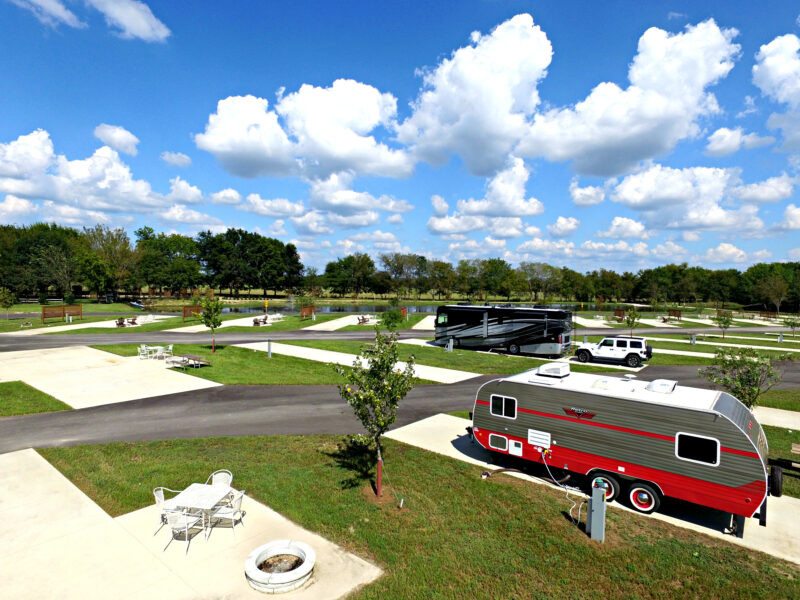 an aerial view of a campground with trailers and rvs parked on concrete pads under a blue sky with clouds
