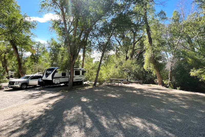 a truck and an rv are parked at a wooded campsite