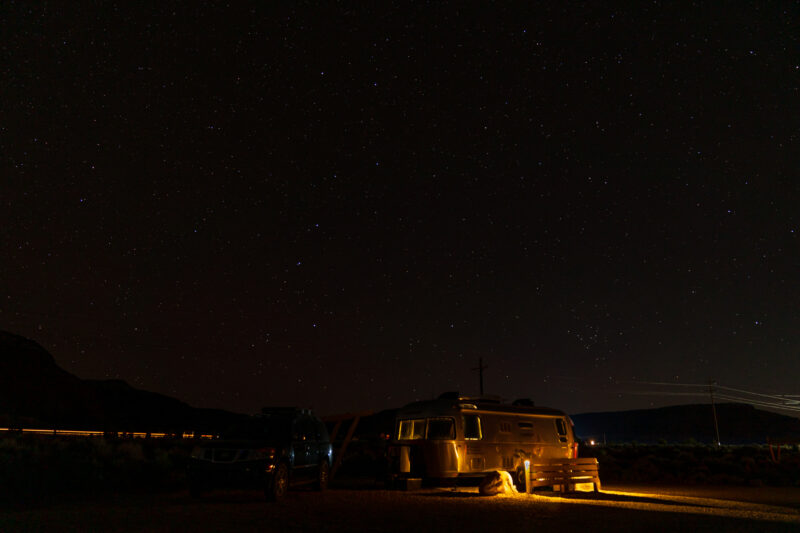 an airstream trailer is parked under a dark sky dotted with stars