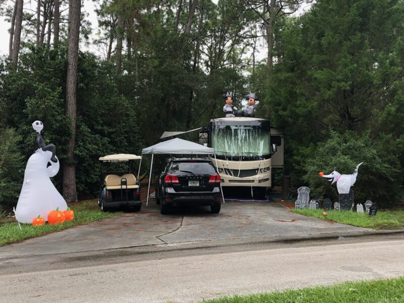 an rv and car parked at a campground surrounded by halloween decorations