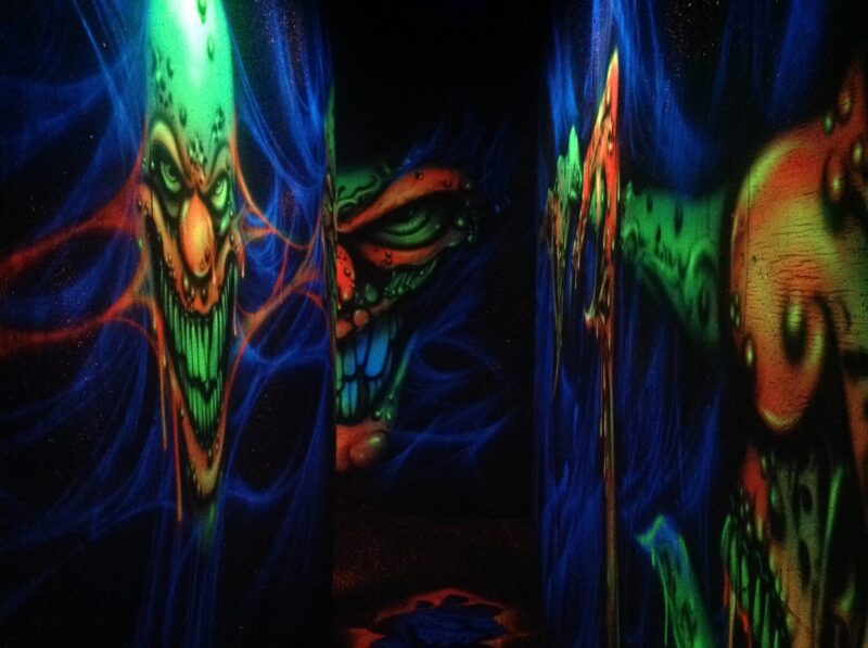 blacklight reactive paintings of clowns in a haunted house