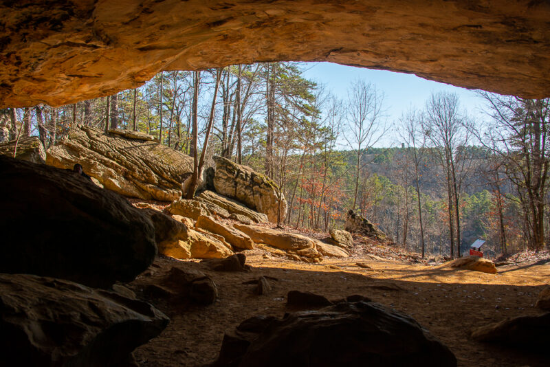 inside of a cave formation looking out at a scenic vista with fall foliage and rocks