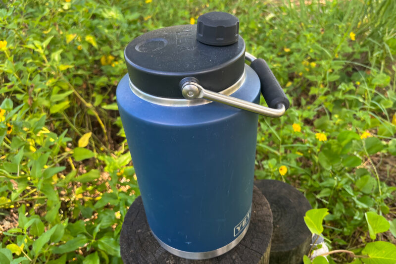 A blue reusable water bottle on a log in the grass