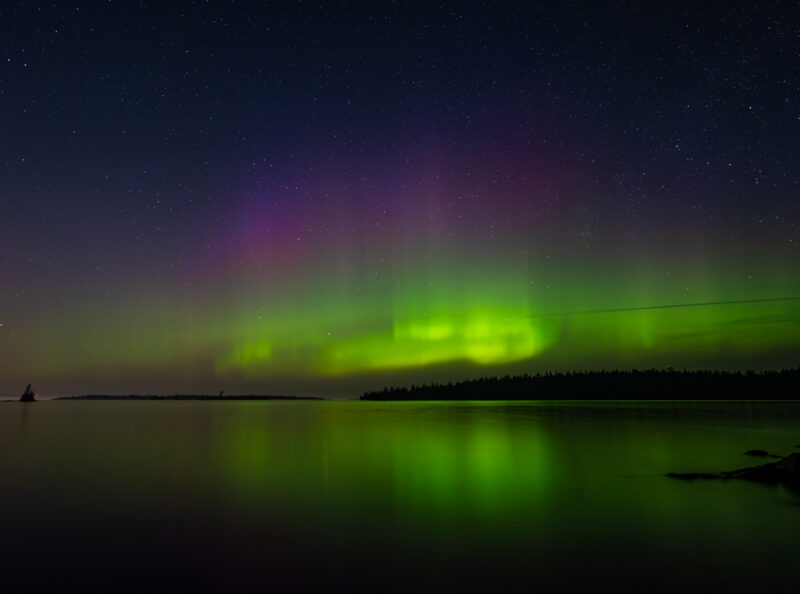 Purple and green auroras dance above Lake Superior from a Lane Cove campsite at Isle Royale National Park, Michigan