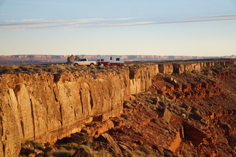 a truck and trailer are parked at the edge of a rock formation in the desert