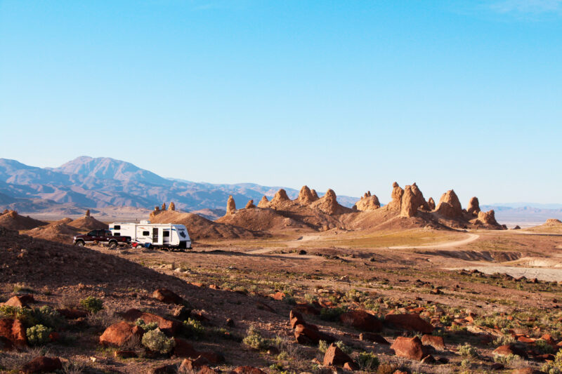 an rv parked at a desert campground surrounded by red rock formations under a clear blue sky