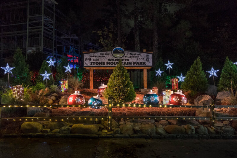 A Christmas tree, larger-than-life ornaments, and lighted decor adorn the entrance to Stone Mountain Park.