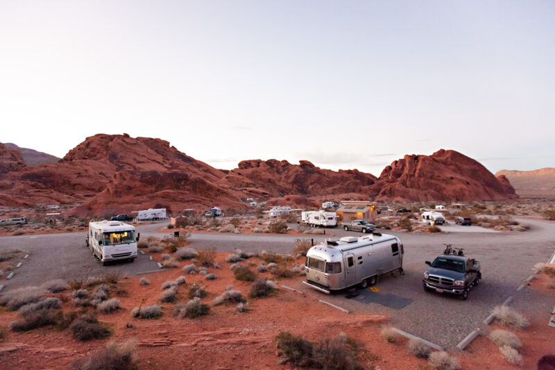 Campers fill roomy spaces at a campground amid red rock formations.