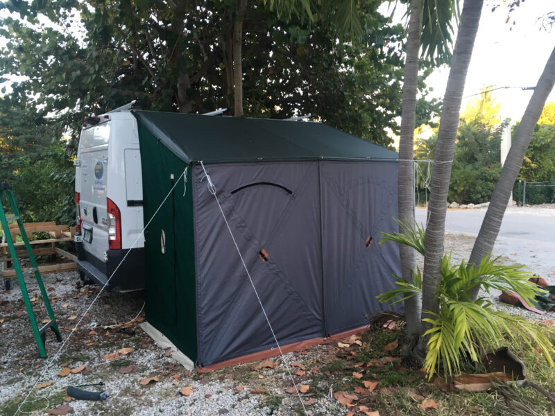 The door of a class B motorhome is covered with a weatherproof tent.