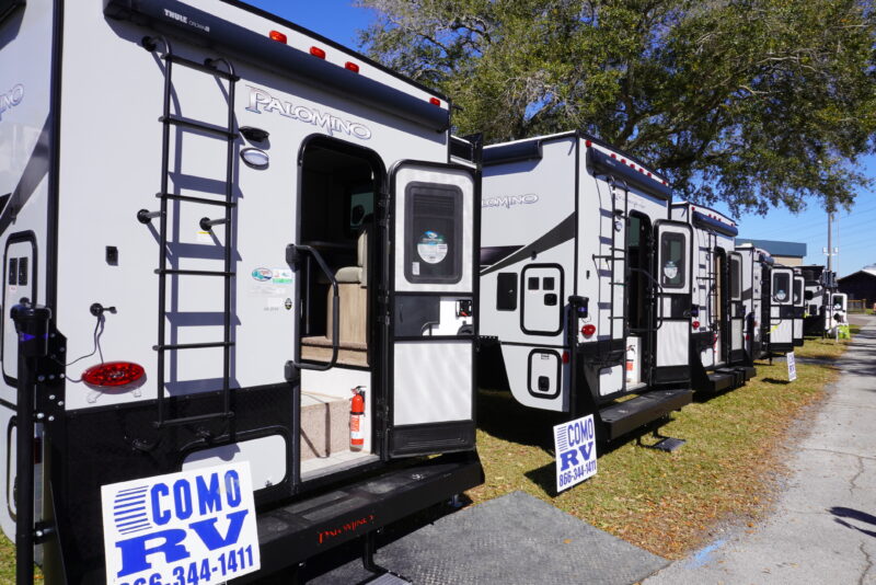 Multiple rigs lined with with their back doors open for viewing at an RV show