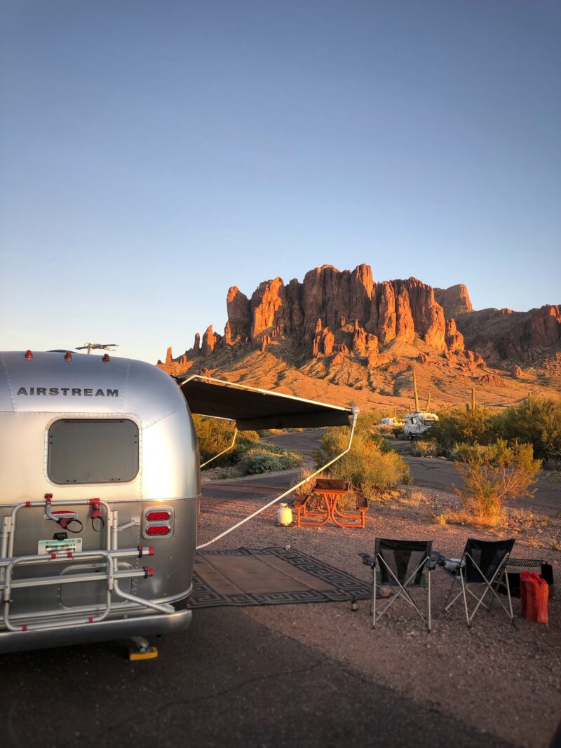 An airstream trailer is parked in a prime spot for looking at soaring red rocks.