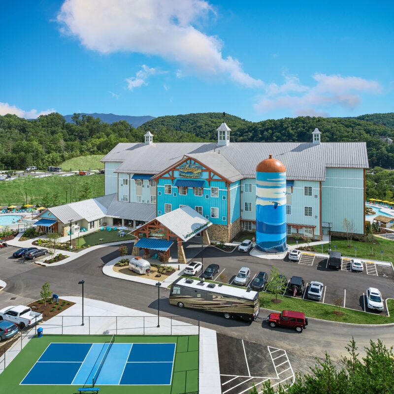 A resort-style building features a pickleball court near its parking lot.
