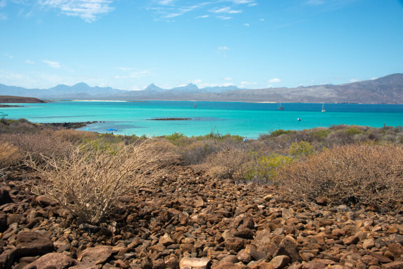 Rugged terrain looks out on teal blue waters.
