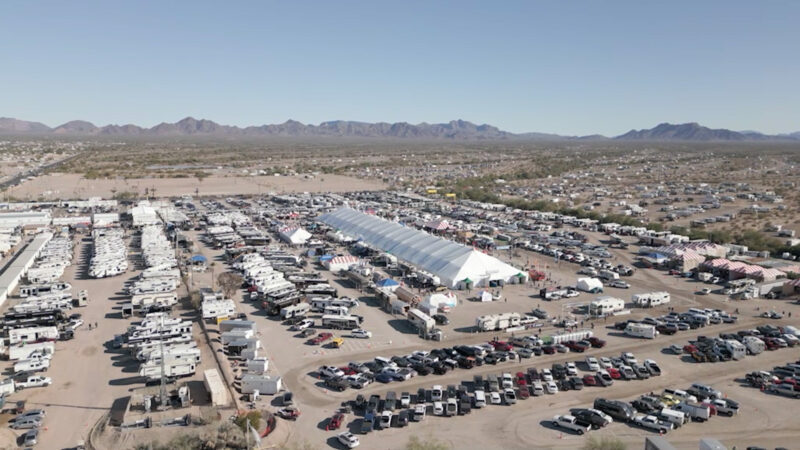 A large desert plain is covered in cars, tents, and RVs.