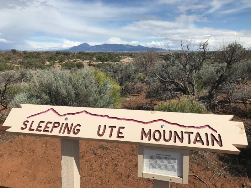 A sign reads "Sleeping Ute Mountain" with the mountain looming in the distance