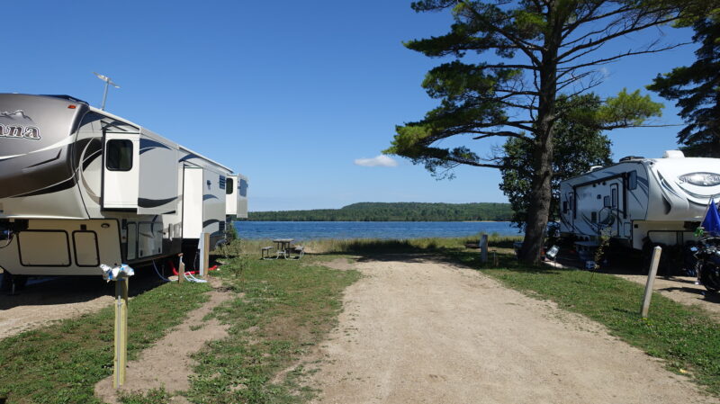 Travel trailer parked at a campsite overlooking a large body of water