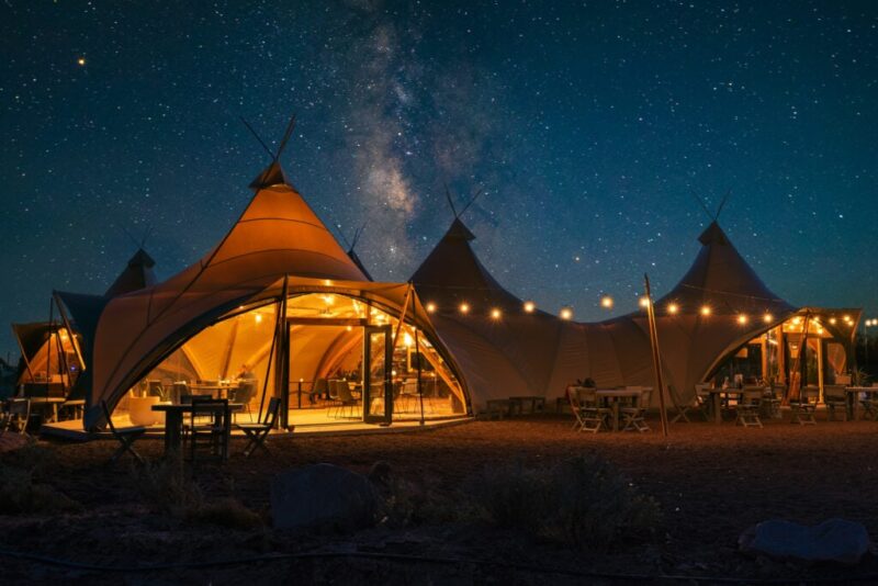 A sky full of stars with glamping tents set up at night