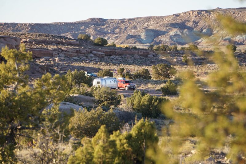 An RV sits tucked back into the brush at a remote camping spot in Utah