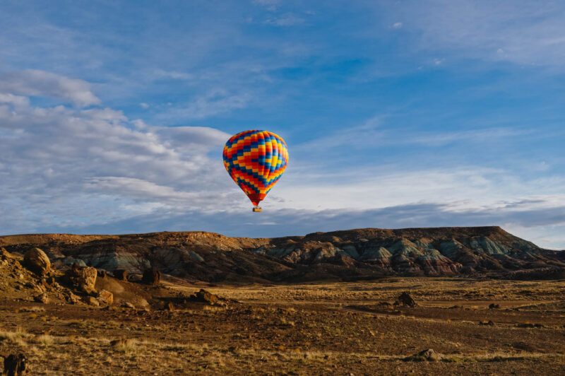 A colorful hot air balloon lands in a field in Moab, Utah