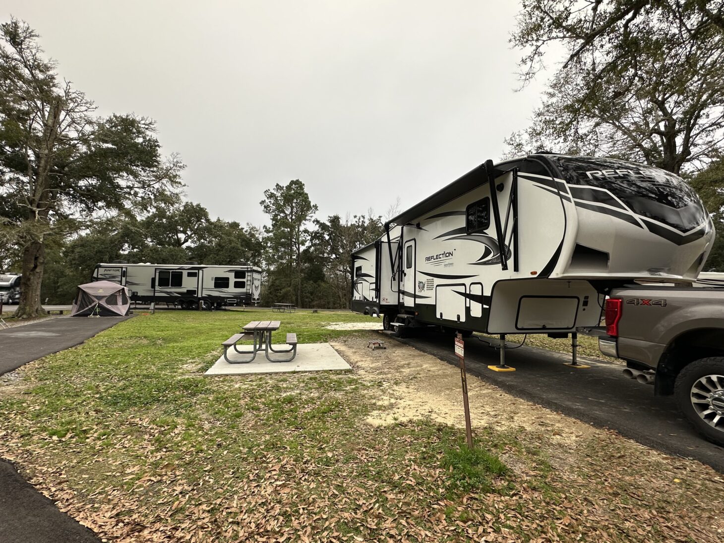 Fifth wheel RV parked at a campsite with a picnic table outside