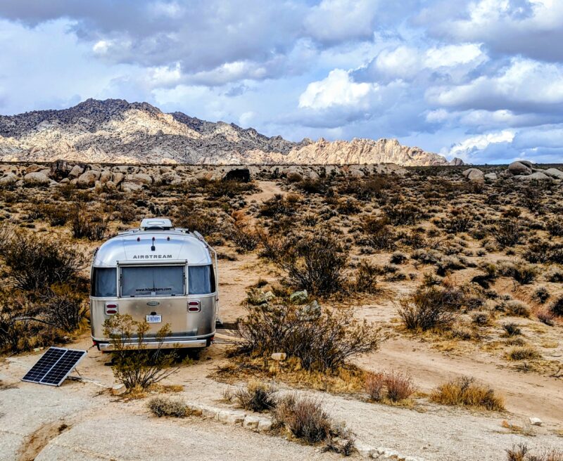 An Airstream trailer stands parked alone amongst a rugged landscape