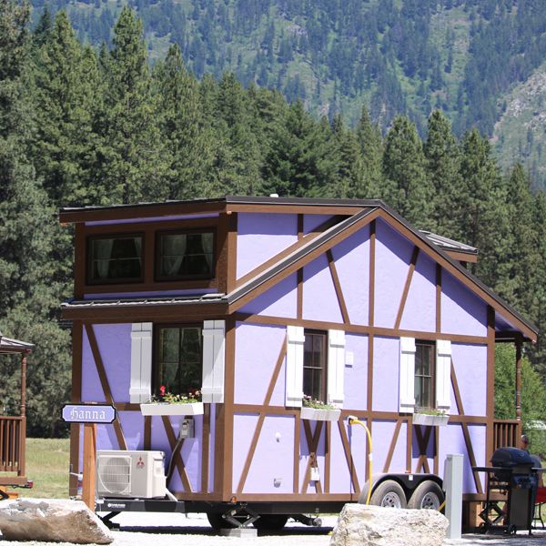 Purple tiny house sitting in a glampground with mountains and trees in the background