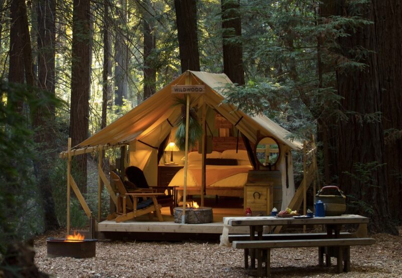 Glamping tent in a wooded area with a picnic table outside