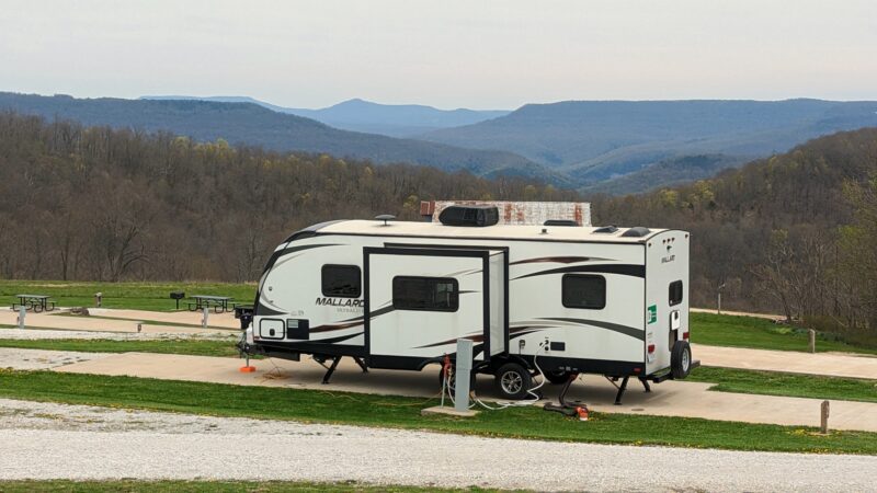 A large camper is parked in a campground overlooking the Ozark Mountains
