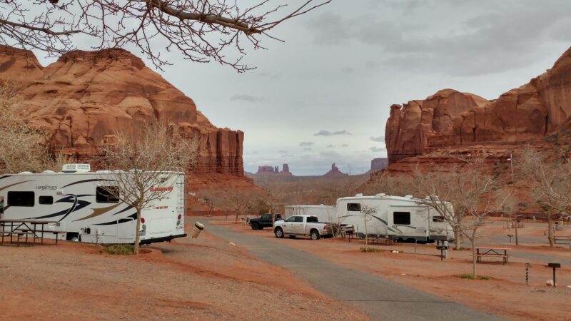 RVs sit in a campground with views of nearby Monument Valley