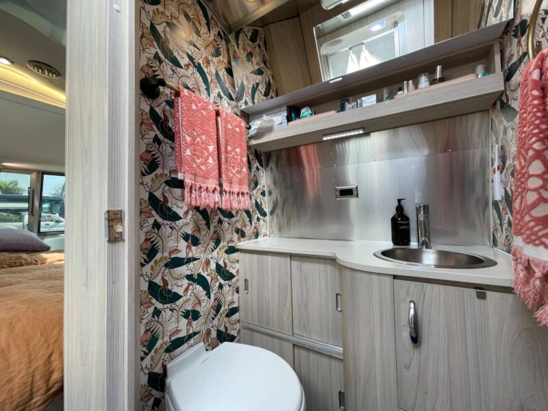 Nicely decorated RV bathroom with colorful wallpaper and organized toiletries