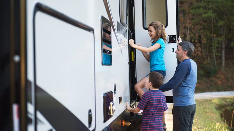 Two kids entering an RV door with an adult supervising