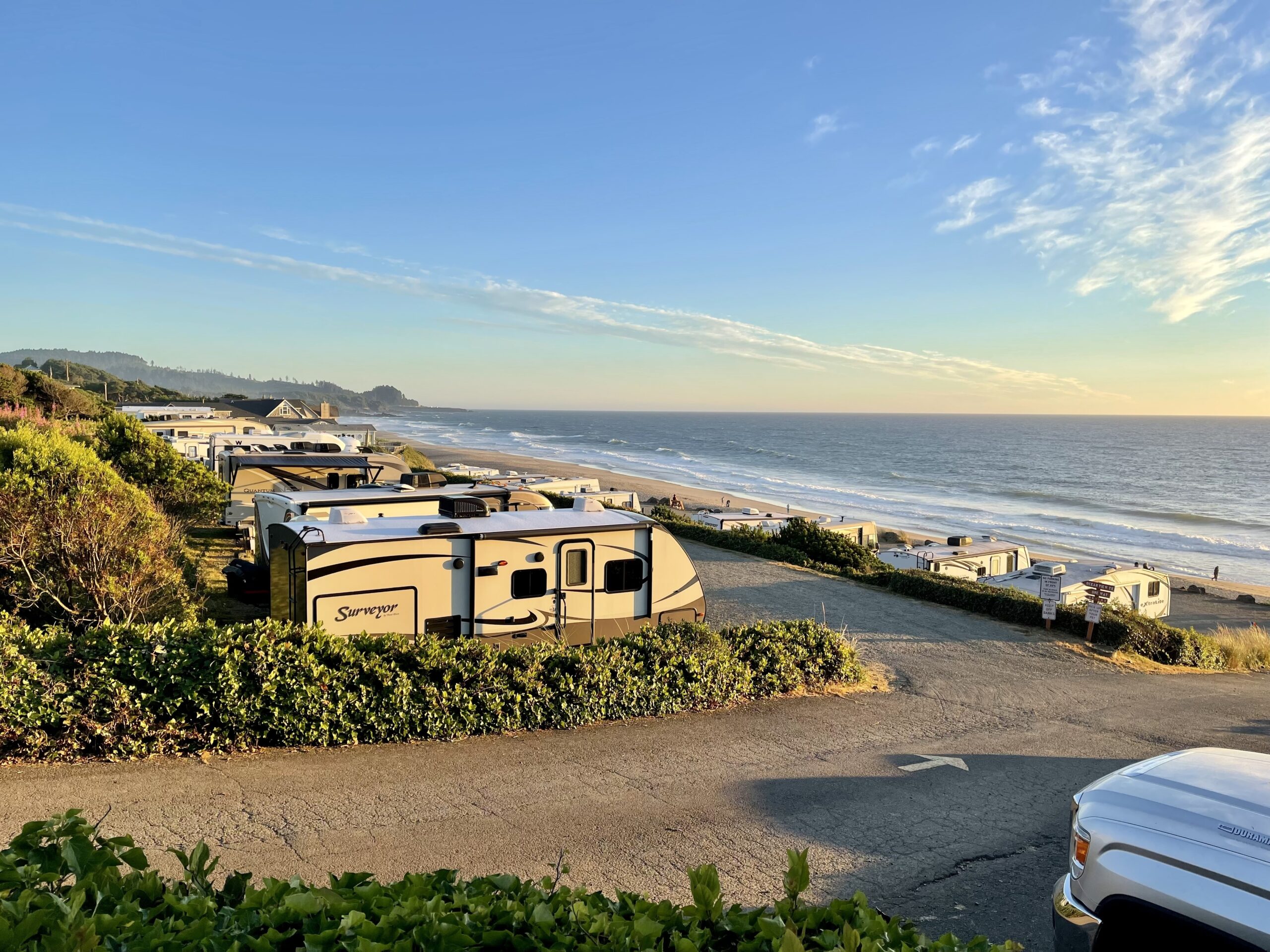 an RV park near the coast with rows of rvs parked near the shore under a blue sky