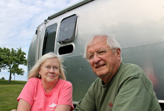 Tom and his wife, Sandy, sitting in front of their Airstream