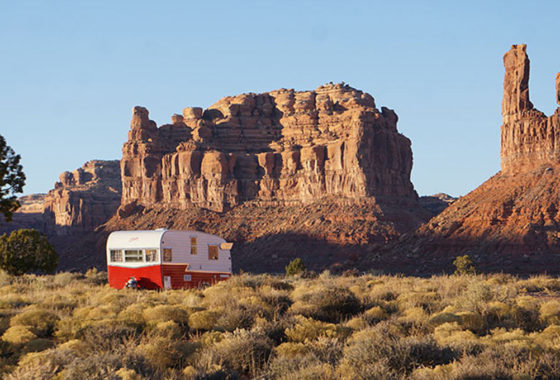 A cute red and white vintage Shasta travel trailer camping for free near a rocky mesa in the United States