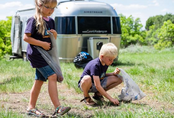 children picking up trash in front of an airstream