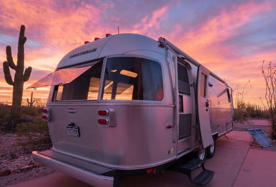 the lavendar and azul blanket of sunset repaints an Airstream travel trailer as it finds itself camping in the midst of a cactus forest in Twin Peaks Campground, Organ Pipe Cactus National Monument