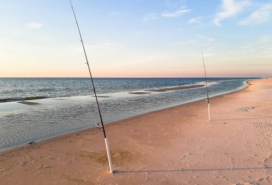Two fishing poles in the ocean at sunset