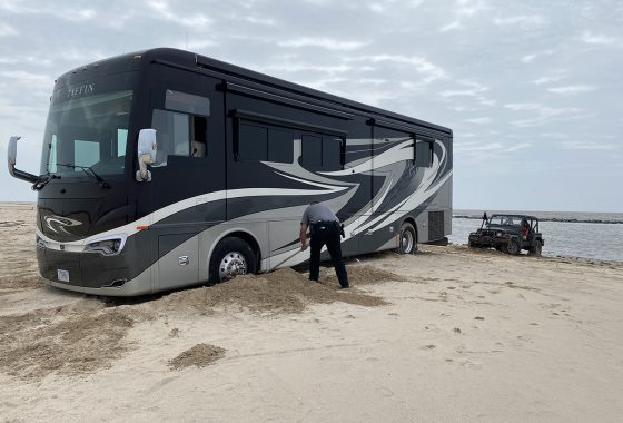 Class A stuck in the sand on a beach.
