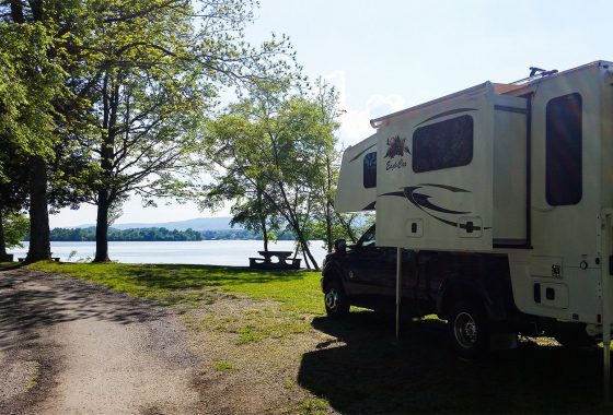 Truck camper parked in front of a lake.