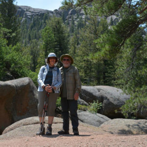 A couple standing in front of rocks and trees.