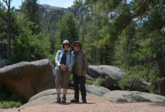 A couple standing in front of rocks and trees.