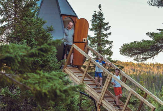 Kids and adults walking out of pod-like glamping accommodations